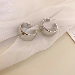 Close-up of polished silver C-shaped chunky hoop earrings with a sleek mirror finish