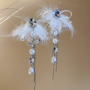 Detailed shot of long tassel earrings featuring white feathers, crystals and pearls