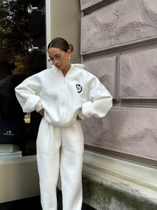 Outdoor shot of white cotton tracksuit set featuring hooded jacket with crown emblem