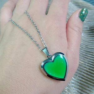 Detailed shot of a silver heart locket necklace changing color to vibrant green