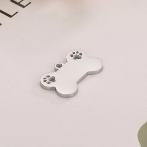 Detailed view of silver bone-shaped metal pendant with cutout paw prints for DIY jewelry