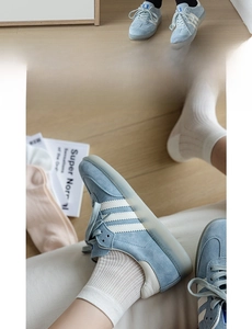Detail of wide elastic cuffs on breathable cotton socks with blue sneakers and white stripes