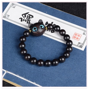 Détail macro du bracelet en bois avec tête de chat sculptée et yeux bleus brillants