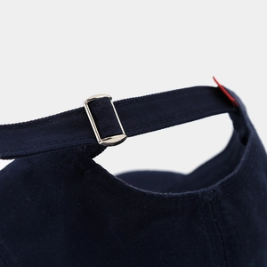 Detailed close-up of the adjustable silver metal buckle on a navy blue cotton baseball cap