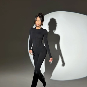 Slim fit black long sleeve jumpsuit for women with waisted design in studio lighting