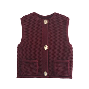 Detail of burgundy chunky knit vest featuring round neck and large glossy buttons