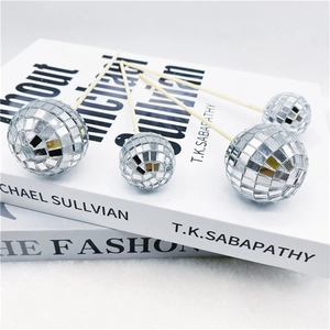 Silver mirror disco ball cake toppers in various sizes placed on elegant books