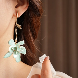 Detail of vintage mint green enamel flower drop earrings worn by a model in soft light