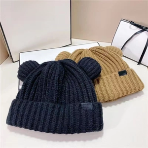 Gros plan de bonnets en maille épaisse avec oreilles d'ours en noir et couleur camel