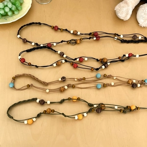 Bohemian beaded waist chain belts in four colors on a light wood background