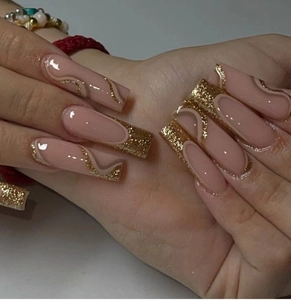 Close-up of long coffin nails with nude base, golden glitter waves, and French tip detail