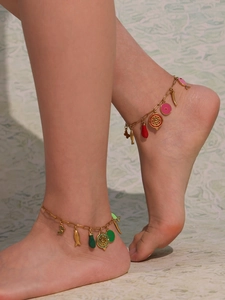 Detail of colorful enamel charms on a gold stainless steel anklet worn by a model