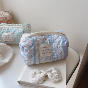 Macro detail of quilted floral cotton makeup bag with French label and zipper closure