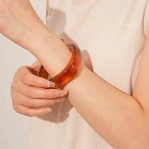 Close-up of amber resin bangle with tortoise shell texture on woman's wrist