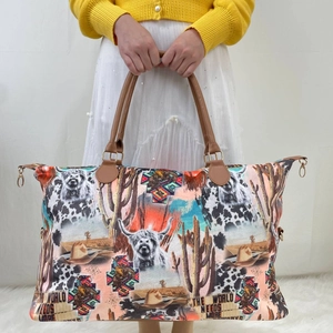 Detail of canvas weekender bag with cowboy motifs and brown leather handles