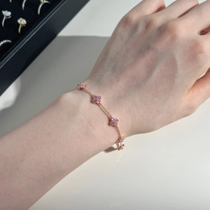 Detail of rose gold clover bracelet with pink zircons worn on a female wrist