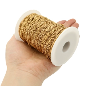 Detailed view of gold stainless steel Cuban link chain wrapped on a white plastic spool