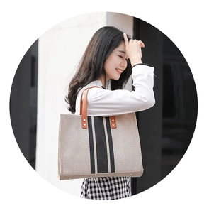 Detail of canvas tote bag showing brown leather handles and black vertical stripes