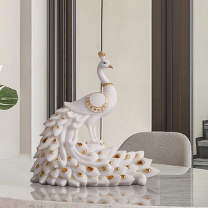 Elegant white peacock figurine with gold details and amber crystals on marble surface