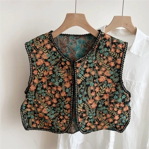 Detailed floral embroidery on black ethnic style vest shawl hanging on a wooden hanger