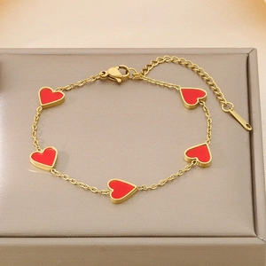 Detail of gold titanium heart bracelet with five red charms on a jewelry box