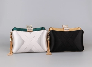 Detail of evening clutch bags showing satin pleated texture and metal tassel accents
