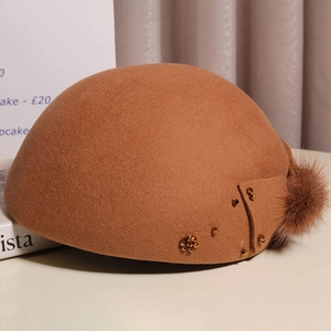Detail of camel wool beret with fuzzy mink fur pompom and amber beaded bow decoration