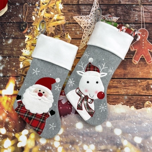 Close-up of gray felt Christmas stockings with 3D Santa and reindeer on wood background