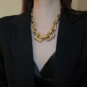 Close-up of chunky gold chain necklace with interlocking square links on a model