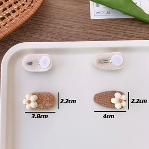 Detailed size view of brown plush and knit hair clips with small white floral accents