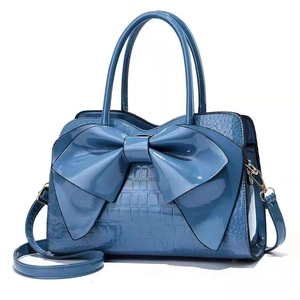 Elegant blue glossy croc-textured handbag with a large bow detail and top handles