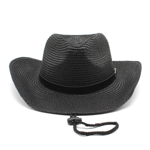 Detail of black straw cowboy hat with woven texture, decorative band, and wind cord
