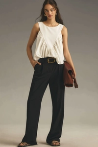 Detailed view of white sleeveless top with V-stitch texture and black trousers styling