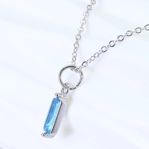 Detailed close-up of a silver rectangular pendant with sparkling blue zircon stone