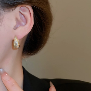 Close-up of elegant gold U-shaped earrings with micro-pave cubic zirconia on model