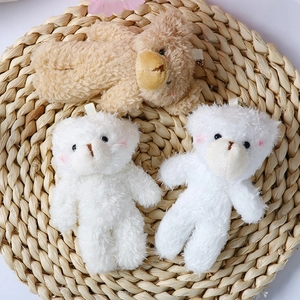 Cute plush teddy bear keychain with pink blush on a woven mat for bags or bouquets