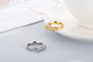 Detail of gold and silver stainless steel rings with oval signet face on textured surface