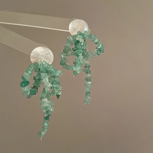 Détail de boucles d'oreilles en argent avec nacre blanche et perles de pierre verte