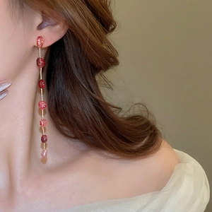 Detailed close-up of long tassel strawberry crystal earrings with gold chains on a model