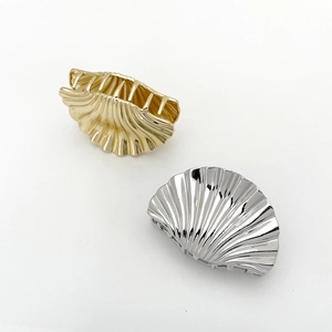 Detail of metallic shell hair clips in gold and silver with textured radial surface
