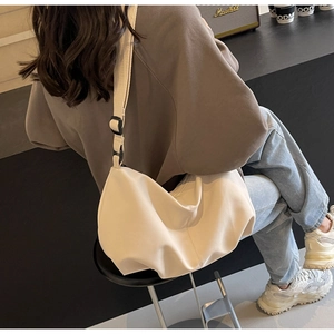 Close-up of beige nylon crossbody tote bag with wide strap and adjustable buckle on model