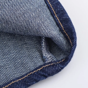Gros plan détaillé du tissu en jean bleu avec des coutures orange renforcées au bord