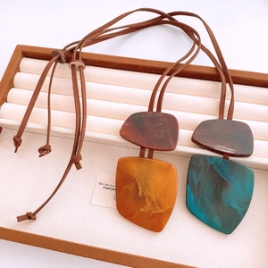 Close-up of vintage resin horn pendants with marble texture on velvet jewelry tray