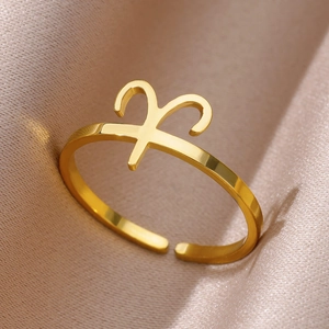Polished golden Aries zodiac sign open ring displayed on silk fabric backdrop