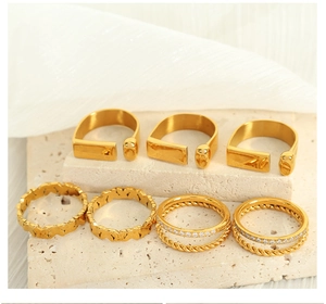 Detailed set of seven gold-plated rings with floral patterns and zircon stones on stone base
