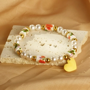 Détail du bracelet en perles avec perles fleurs en résine et pendentif cœur doré