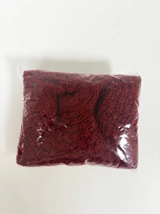 Falda de árbol de Navidad de punto rojo vino doblada en bolsa de plástico transparente