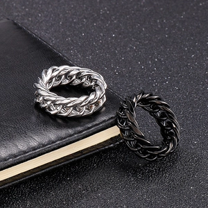 Macro shot of silver and black stainless steel chain rings on dark leather texture