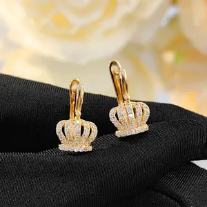 Elegant gold crown hoop earrings with sparkling cubic zirconia on black fabric background