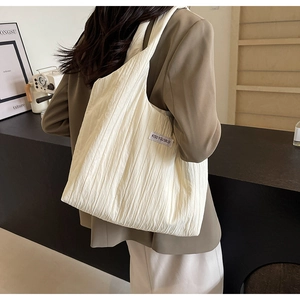 Detailansicht der cremeweißen Totebag mit Texturstoff und kleinem Seitenlabel